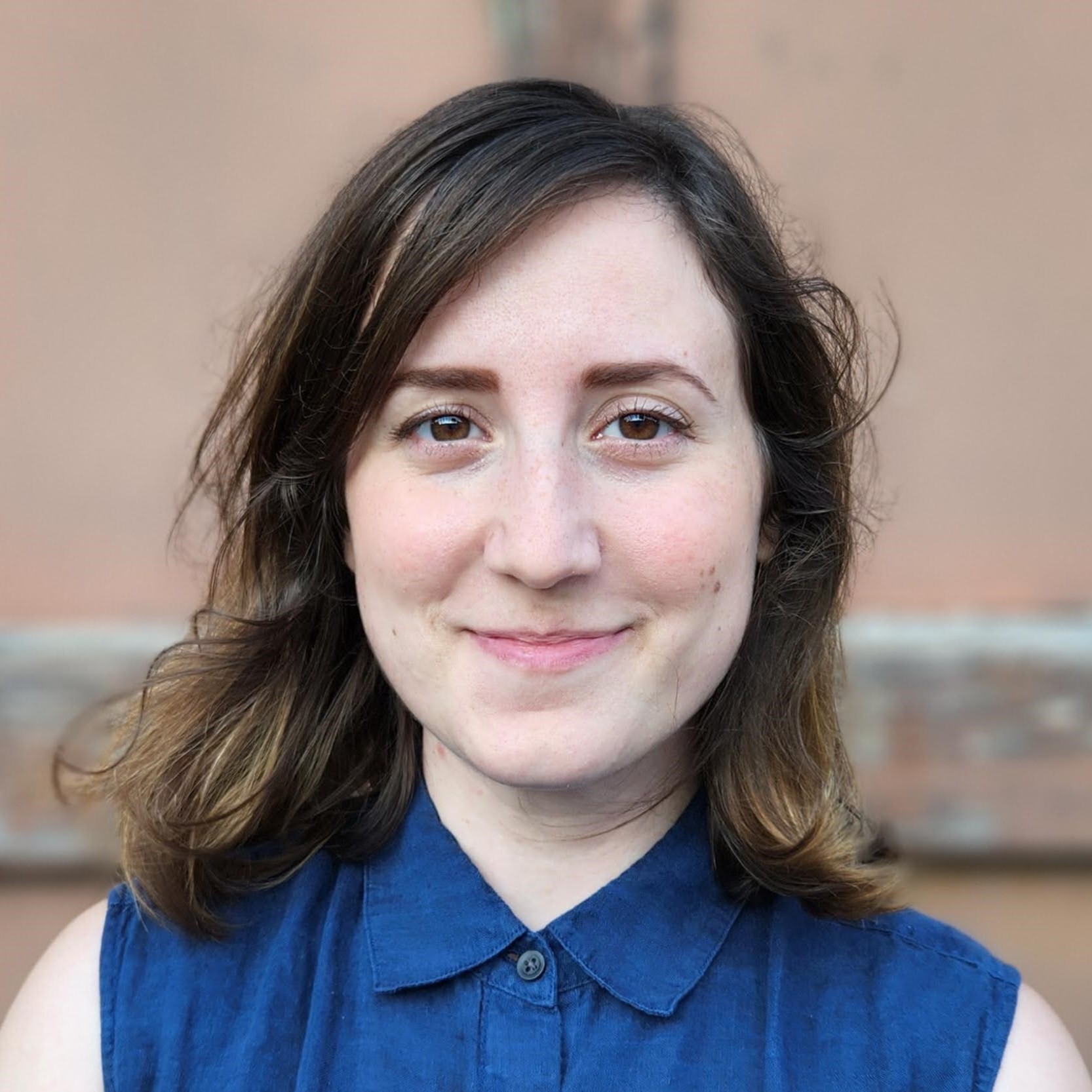 Headshot of Gabriella Penev, she is wearing a blue button up sleeveless shirt and is smiling at the camera.